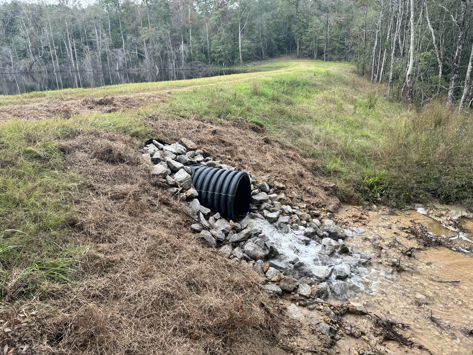 Installed culvert with rock protection near a pond embankment